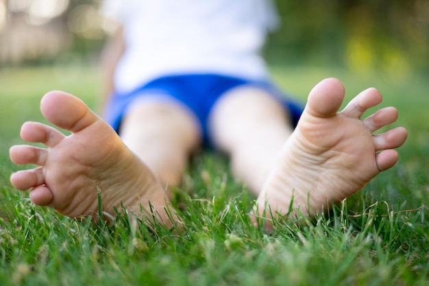 Barefoot feet closeup a child sitting on the grass in the summer in the park