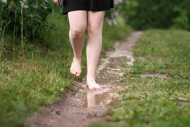 Barefoot girl walks through a puddles of water after the summer rain in countryside.