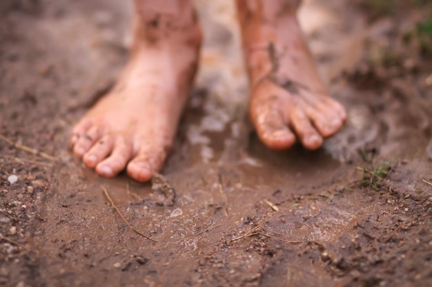 Barefoot girl walks through a puddles of water after the summer rain in countryside.