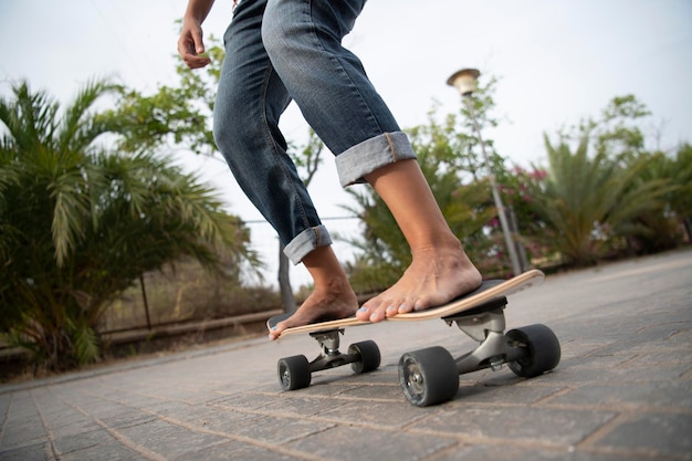 Barefoot girl with nail polish on her nails skates on the\
asphalt