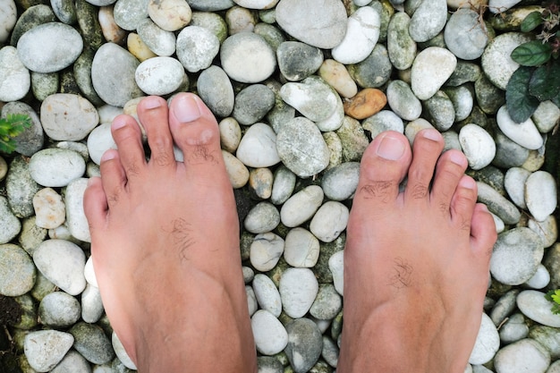 Barefoot guy walking above the white stones. Top view