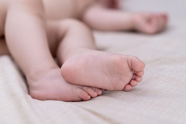 Barefoot little boy lying on white sheet laid on soft bed in nursery in early morning