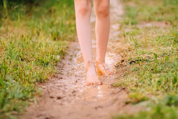 Barefoot meisje loopt door een plassen water na de zomerregen op het platteland.