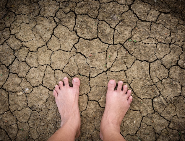 Barefoot standing on dry and cracked ground background and texture