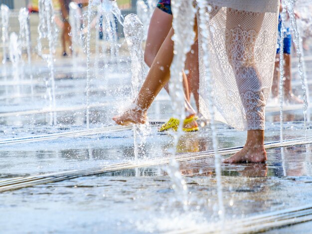 A barefoot woman escapes the heat in splashes of water in a\
city fountain