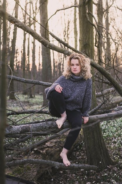 Barefoot woman sitting on fallen tree scenic photography