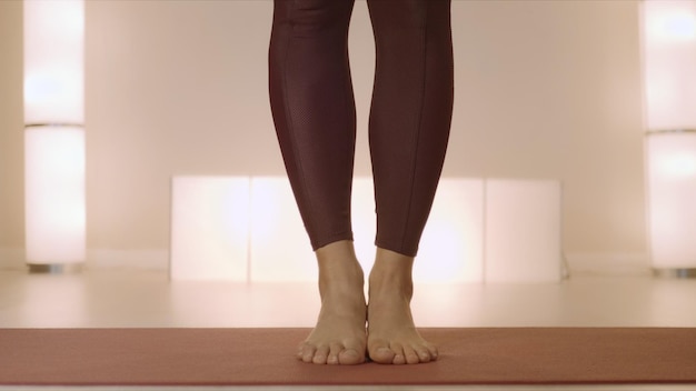 Barefoot woman standing on mat in class Woman legs doing tree pose in studio