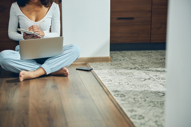 barefoot young female with dark curly hair writing with a pencil