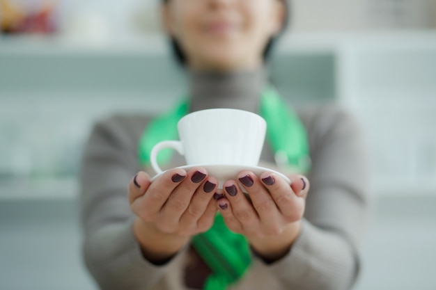 コーヒーショップのエプロンのバリスタは、顧客にtoれたての新鮮なコーヒーを与える