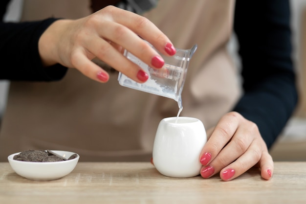 エプロンのバリスタはカップにミルクを注ぎます。コーヒーショップで働くバリスタ