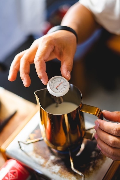 Photo barista boil hot milk in jar and test temperaturemilk use mix in coffee make foam latte coffee