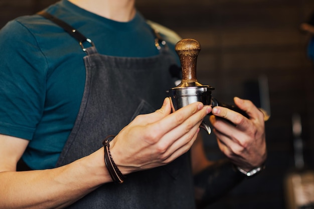 Foto il barista pressa con cura il caffè macinato utilizzando il pressino