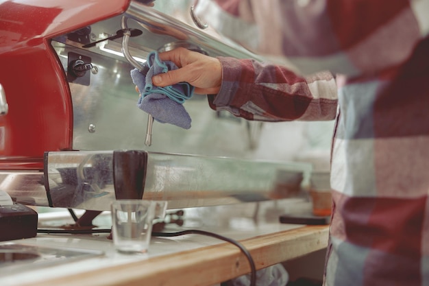 コーヒーメーカーの蒸気蛇口を掃除するバリスタ