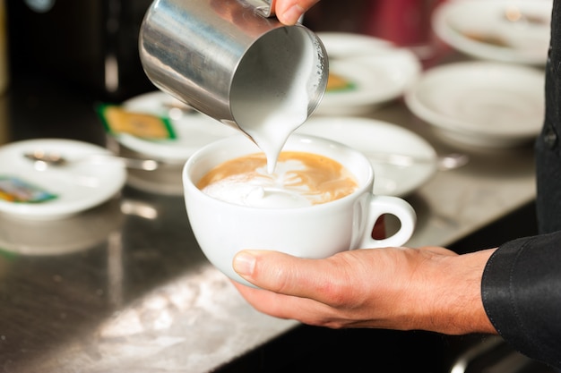 Barista die cappuccino maakt in zijn coffeeshop