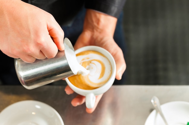 Barista die cappuccino maakt in zijn coffeeshop