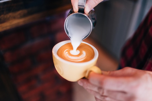 Barista die een koffiezetapparaat gebruikt en verse koffie bereidt met latte-schuim in de koffiebar en restaurantbar of bistro