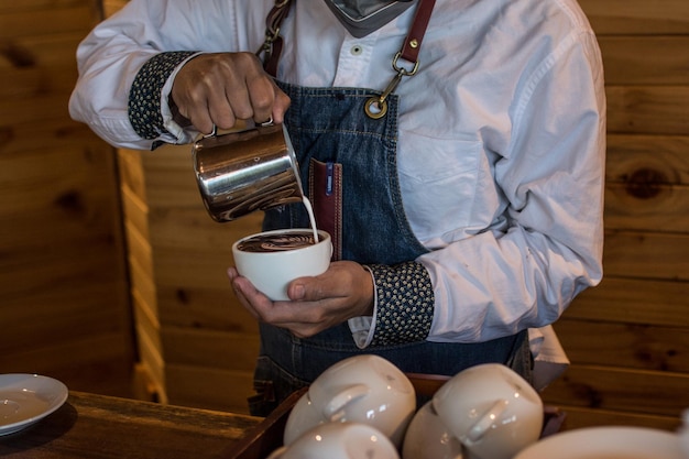 Barista die een kopje koffie latte art maakt