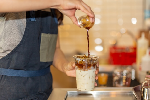 Barista die koffie gieten aan meeneemkop aan het maken van bevroren koffie latte in het koffie.