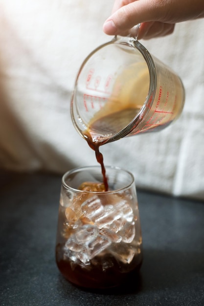 Barista die koffie in een glas giet
