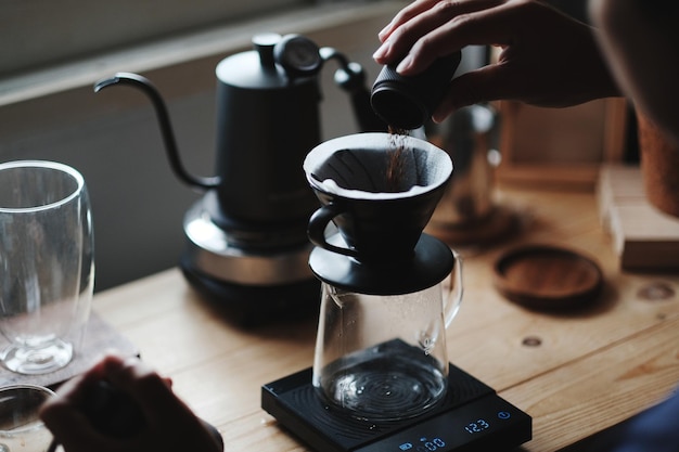 Foto barista druppelt koffie in de ochtend op een houten tafel met vintage decoraties interieurontwerp