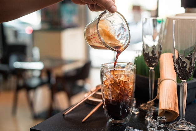 Barista giet melk in een glas ijskoffie