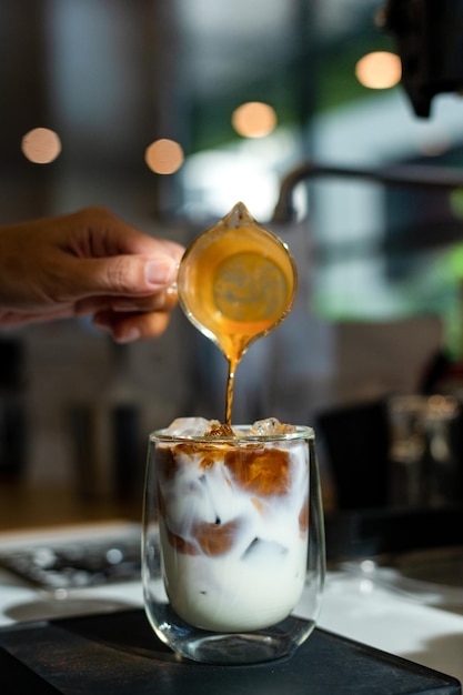 barista giet melk in een glas met ijskoffie