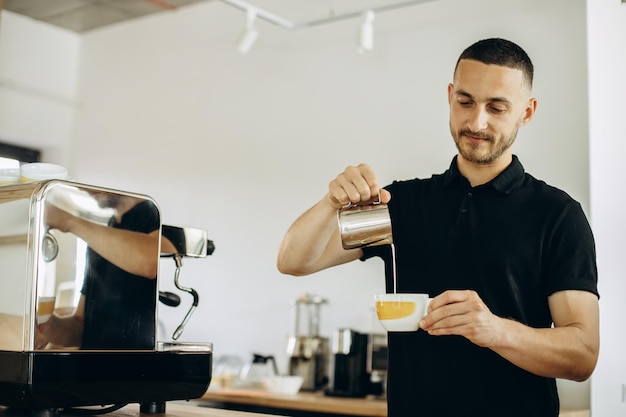 Barista giet melk in een kopje met cappuccino