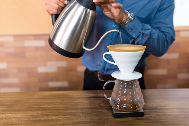 Barista giet water op koffie met filter in café