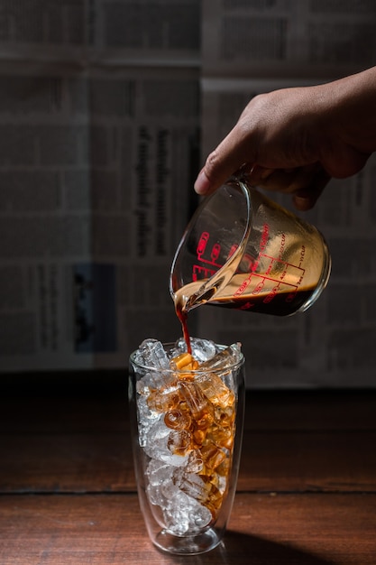 Barista gieten melk in een glas ijskoffie