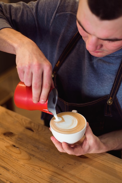 Barista gieten melk in koffiekopje voor latte art.