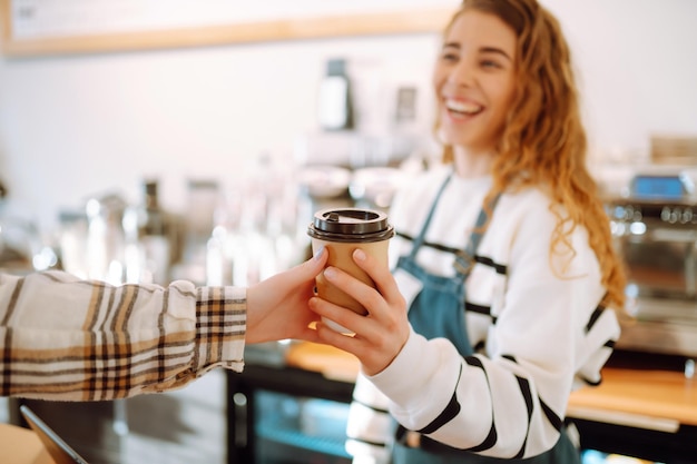 カフェショップでコーヒーをテイクアウトするバリスタの女の子