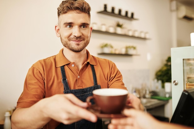 ウェイターにコーヒーを与えるバリスタ