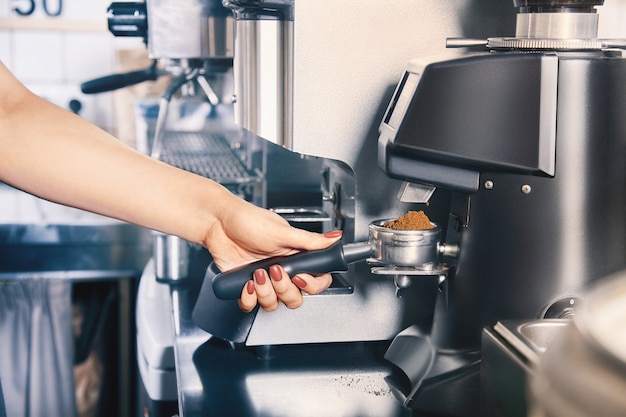 Barista grinding coffee beans using coffee machine. Coffee shop and barista concept. coffee grinder grinding freshly roasted make beans. barista hand hold grinding