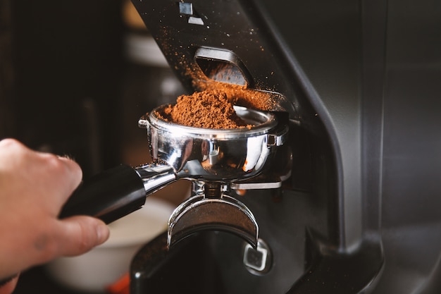 Foto barista macinando i chicchi di caffè usando la macchina per il caffè