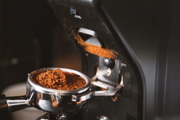 Photo barista grinding coffee beans using coffee machine
