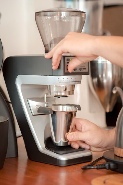 Mano del barista che fa il caffè con macinacaffè