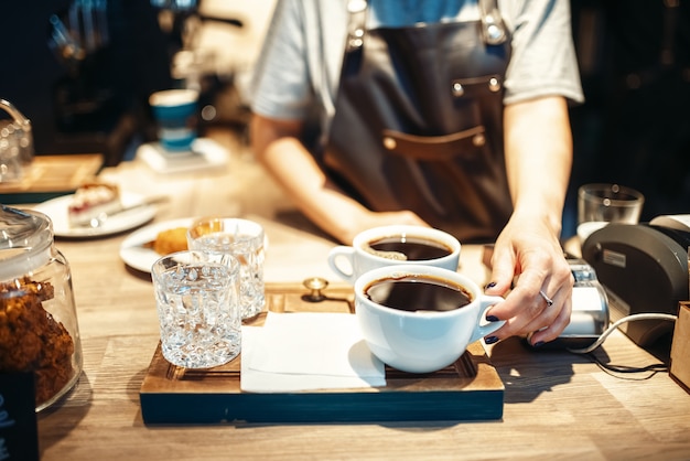 Photo barista hand with cup of fresh hot black coffee