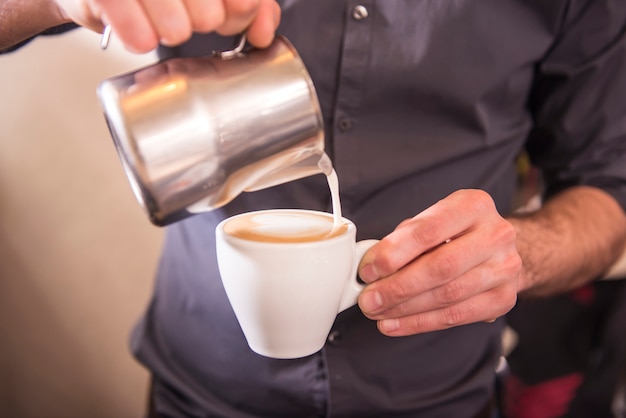 Barista handen giet melk cappuccino maken.