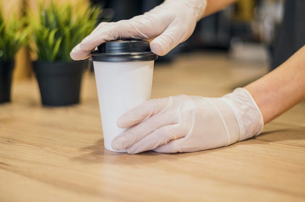 Foto barista che maneggia la tazza di caffè con guanti in lattice