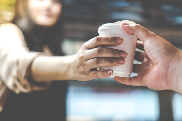 バリスタはコーヒーショップで顧客に提供するために一杯のコーヒーを持っています