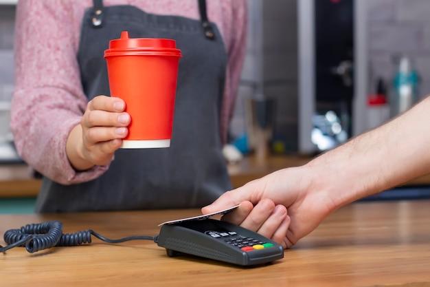 Barista holds out a red paper glass with a drink