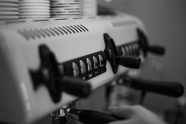 Barista houdt een houder vast en zet koffie met een dubbelboiler koffiezetapparaat