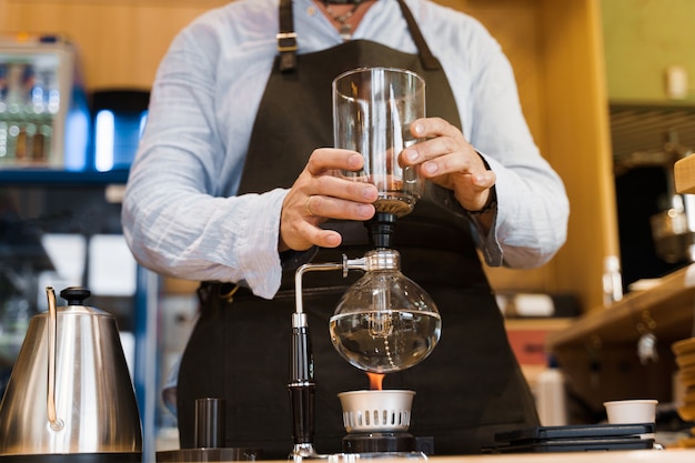 Barista houdt sifon apparaat in handen voordat koffie brouwen in café