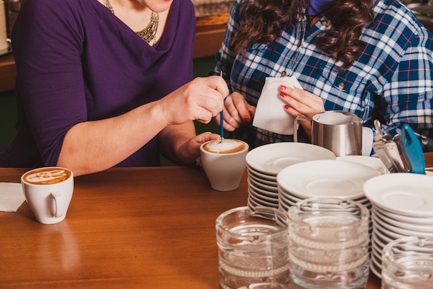 Barista laat zien hoe je latte art koffie maakt. les met speciaal metalen apparaat - latte-art pentool.