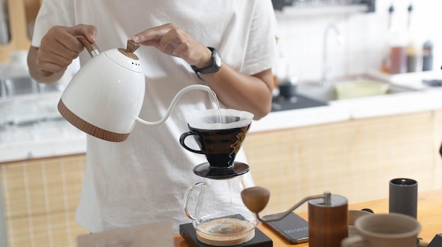 Barista maakt druppelkoffie met heet water en filterpapier in de coffeeshop