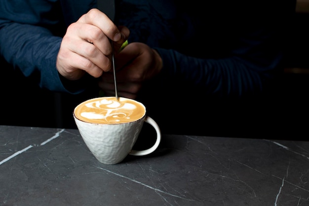 Barista maakt latte art in een coffeeshop in de ochtend een man tekent een bloem op koffie close-up