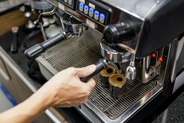 バリスタがカフェアングルビューショットでコーヒーマシンでブラックコーヒーを作る