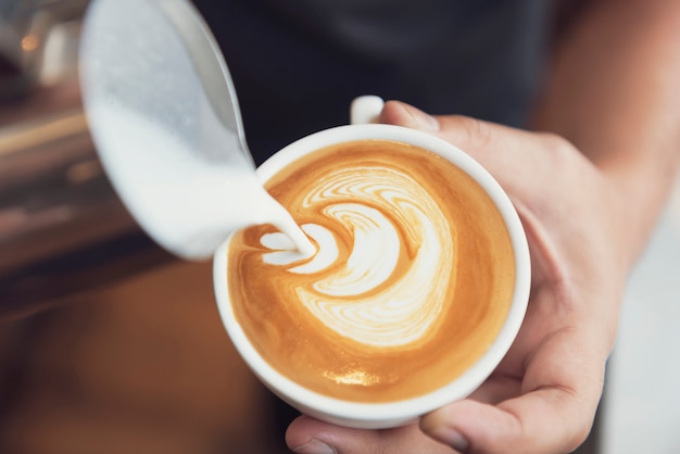 泡立てた泡、カフェでコーヒーカップとラテやカプチーノアートを作るバリスタ。