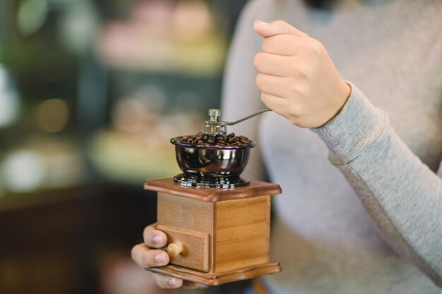 Barista malen koffie met de hand op een vintage koffiemolen