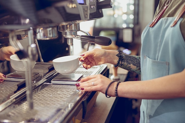 Barista met behulp van professionele koffiemachine in koffiehuis